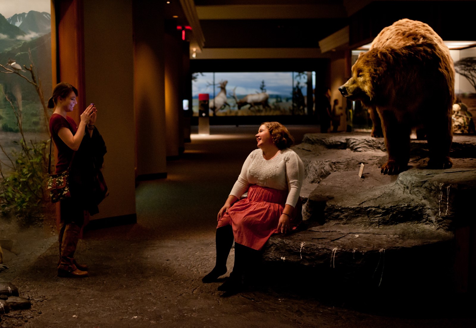 A woman poses for a picture in front of a taxidermy bear in the Carnegie Museum of History.