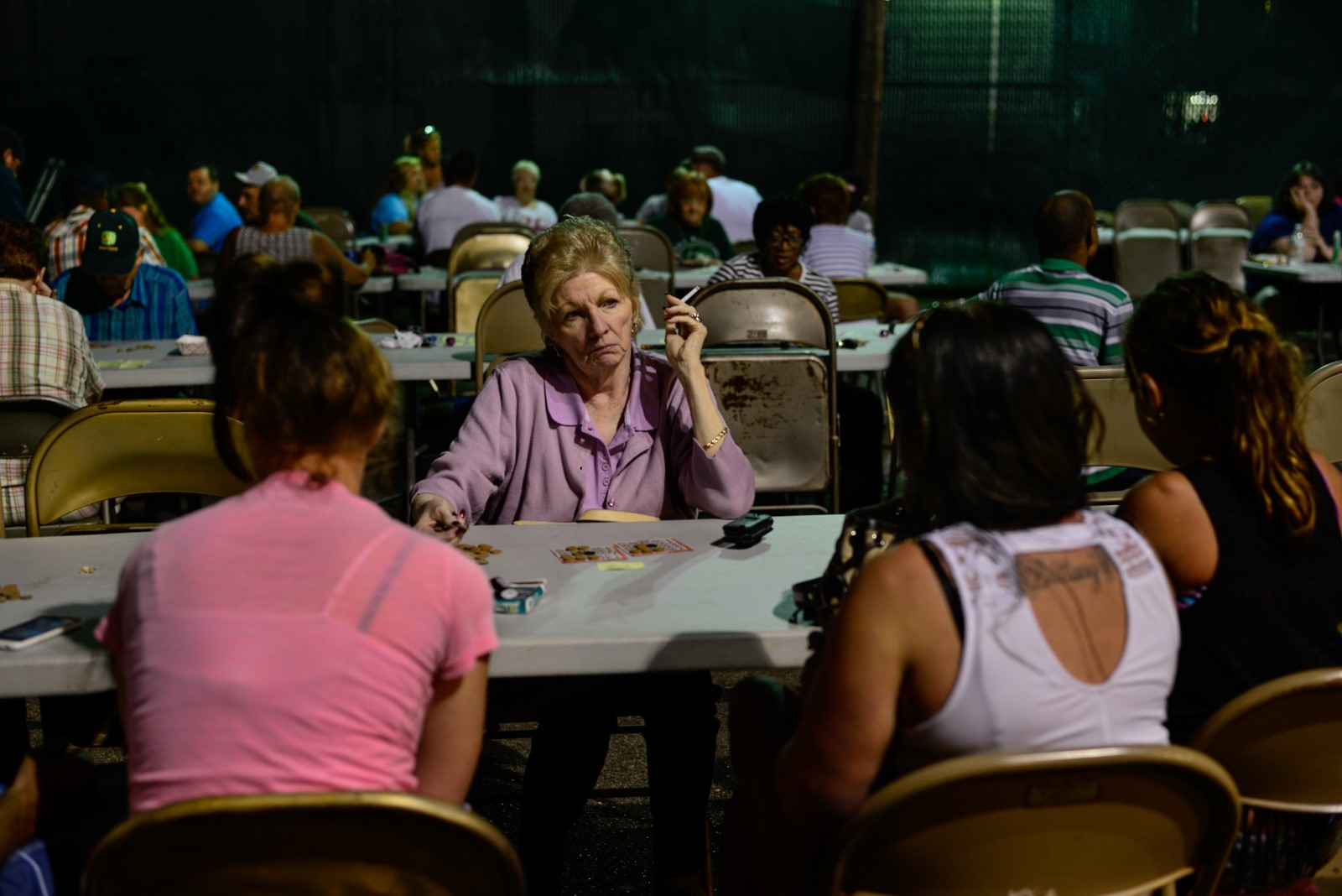 A large group of women, at different tables, play bingo.