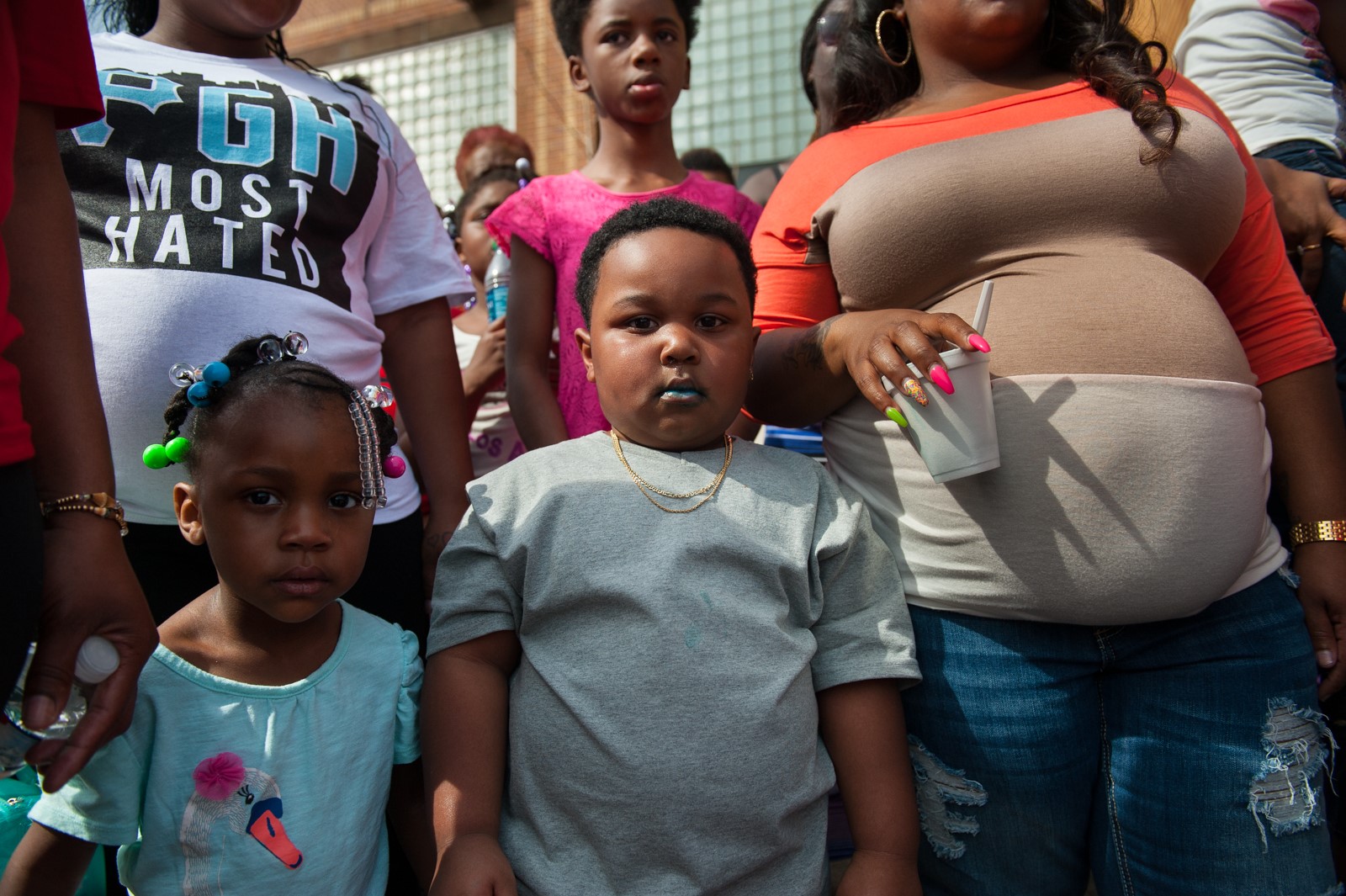 Two children in a crowd stare at the camera.