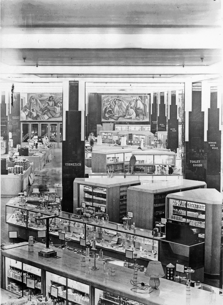View of a department store floor, with glass cases advertising cosmetics and toiletries.