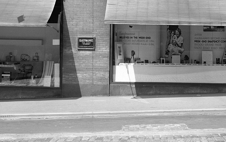 Black and white photograph of a glass storefront and displays.