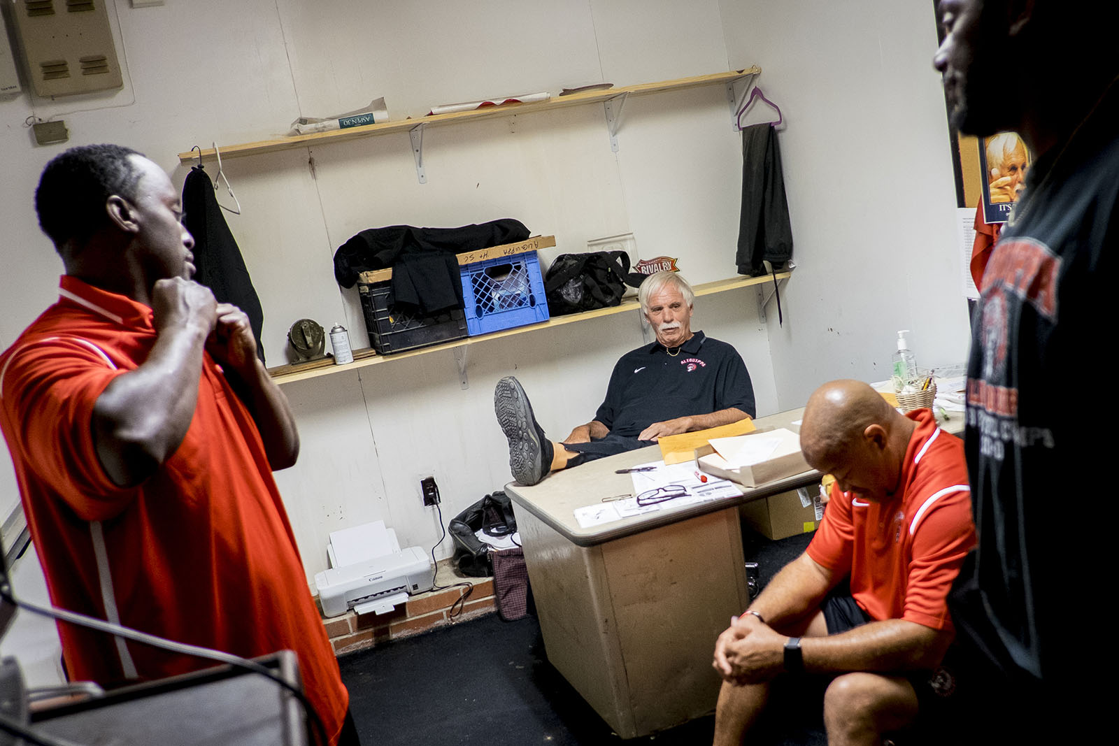 Head high school football coach meets with his staff before a game.