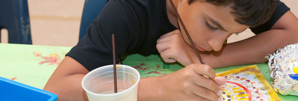 A child intently painting with watercolor paints