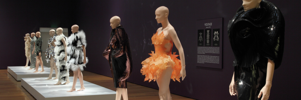A gallery space filled with mannequins dressed in dresses of various color and texture