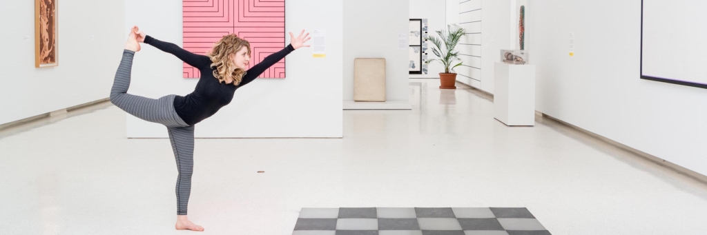 Woman doing yoga pose, standing on one leg in an art gallery