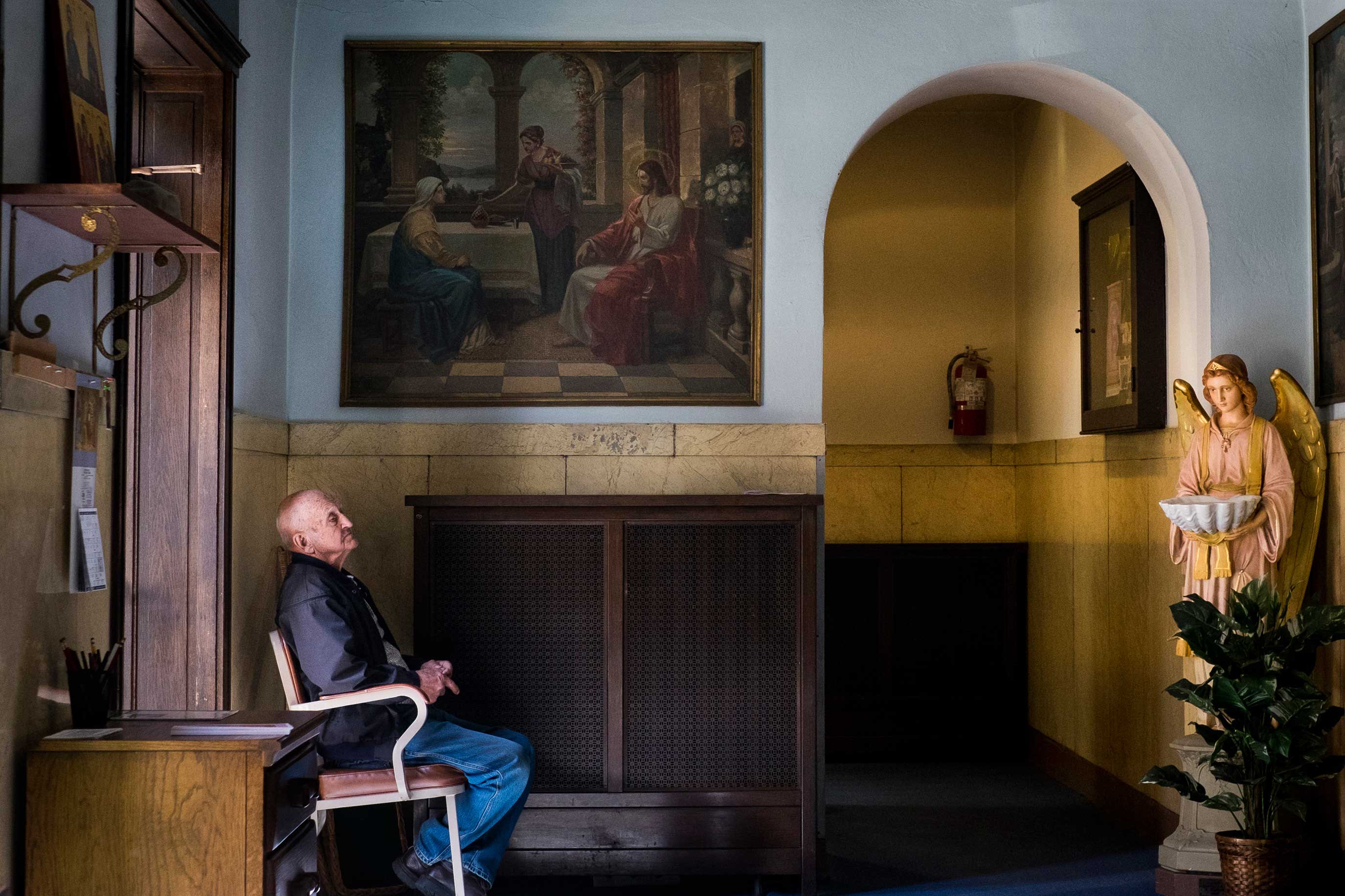 A parishioner sits in the entrance to the church during Sunday Service at Saints Peter and Paul Byzantine Catholic Church in Braddock, Pa.