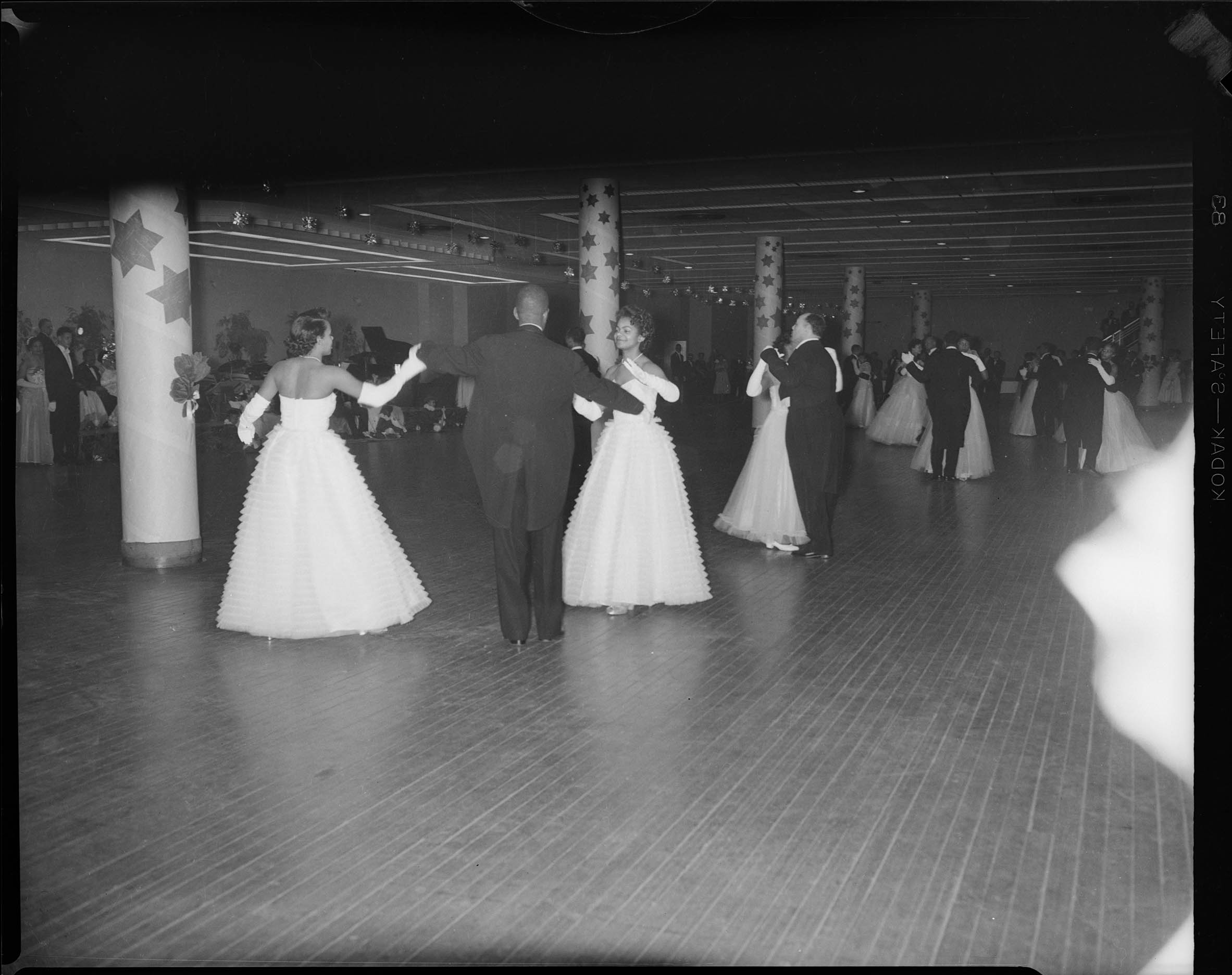 Ballroom, with women in billowing gowns dancing with men in suits