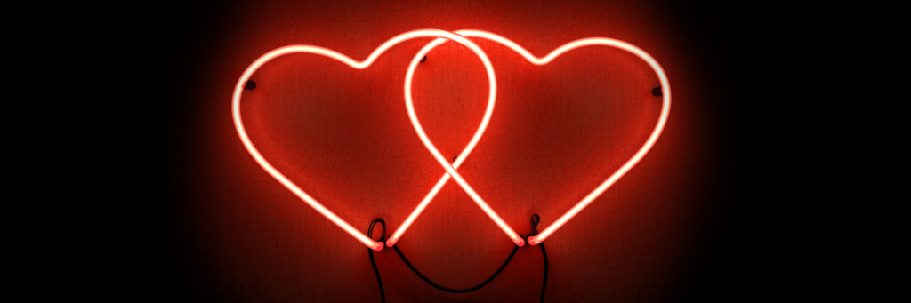 A neon sign of two red glowing hearts intersecting in the center