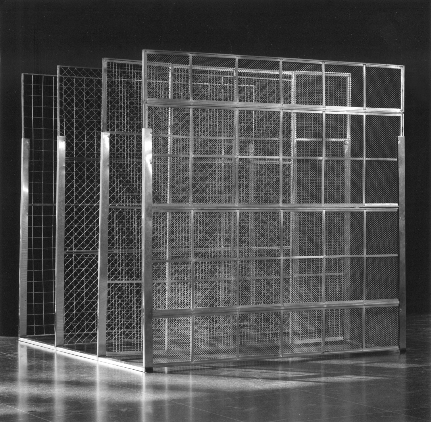 A three-quarter view of a sculpture. Four metallic screens, each with a different pattern of mesh, stand in parallel.
