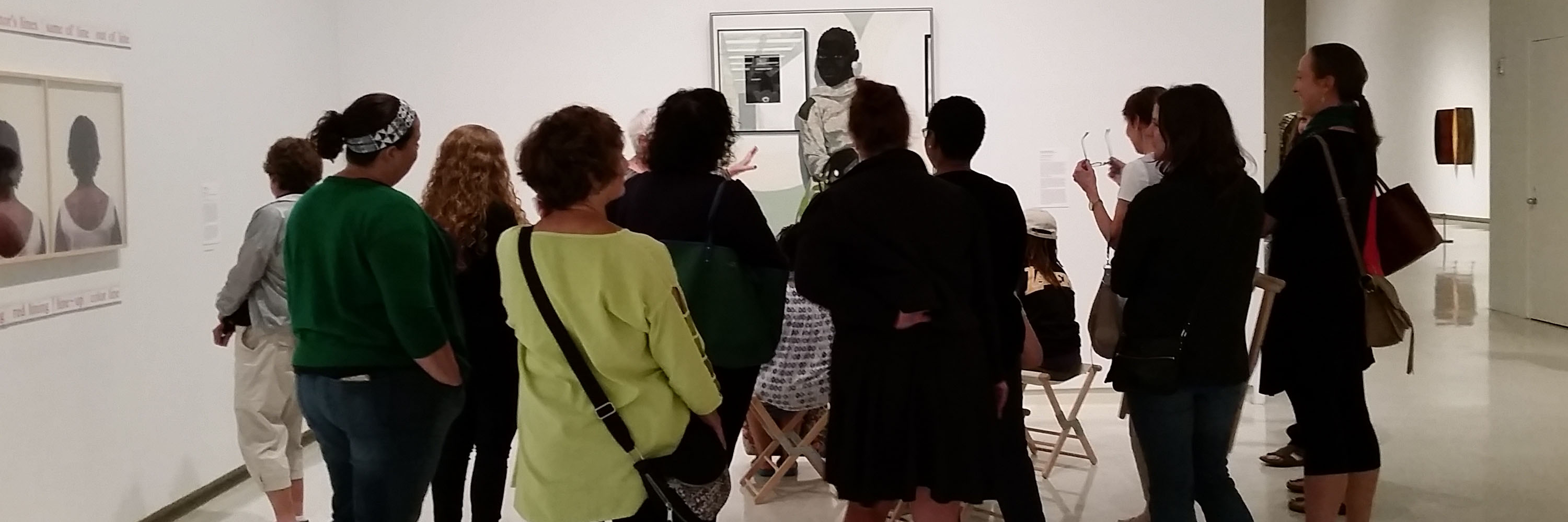 A group of teachers stand around a painting in a discussion