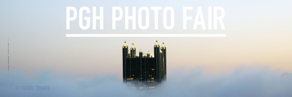 A photo of a tall glass building peeking through the top of clouds with bold text at the top reading PGH photo fair