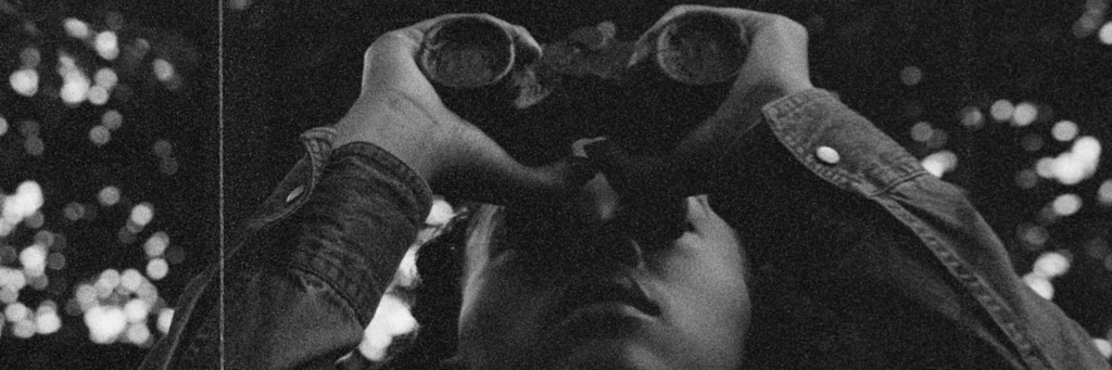 Film still of a person holding binoculars up to their eyes