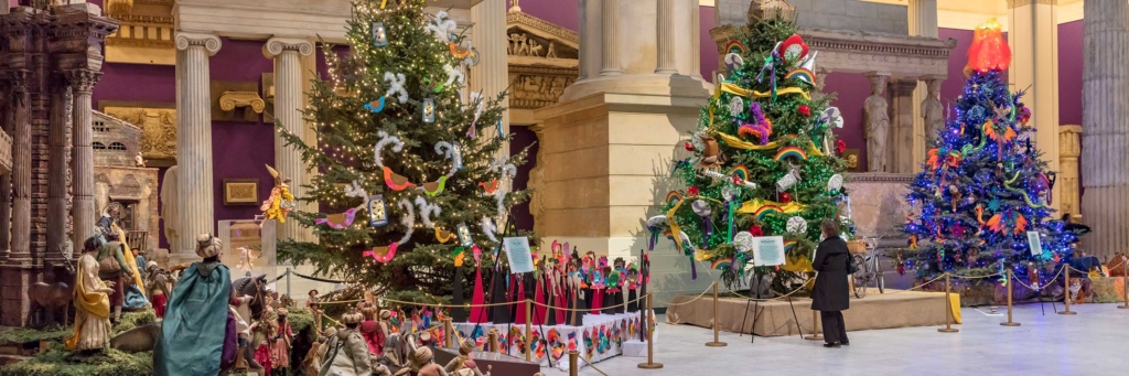 A nativity scene sits in the Hall of Architecture beside large decorated holiday trees.