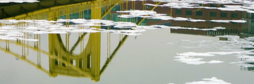 An upside-down yellow bridge with clouds.