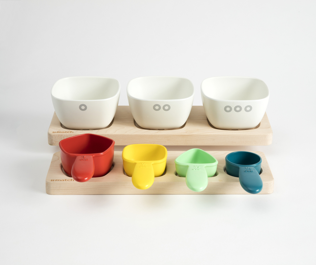 Three bowls and four colorful measuring cups displayed in a wooden carrier.