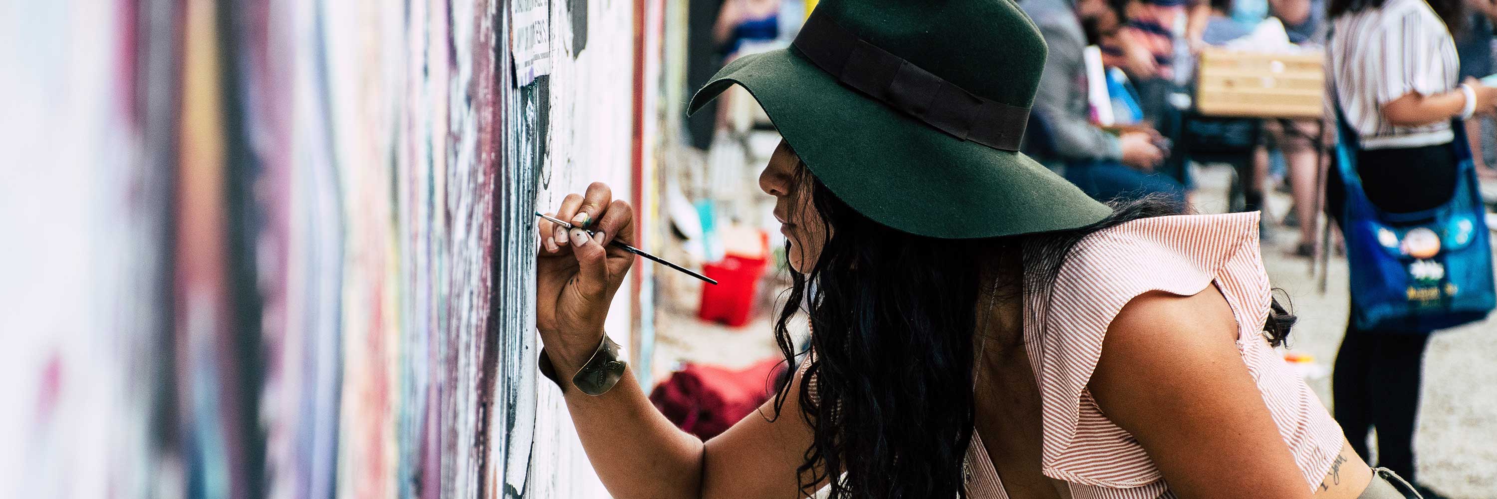 Young woman paints a mural.