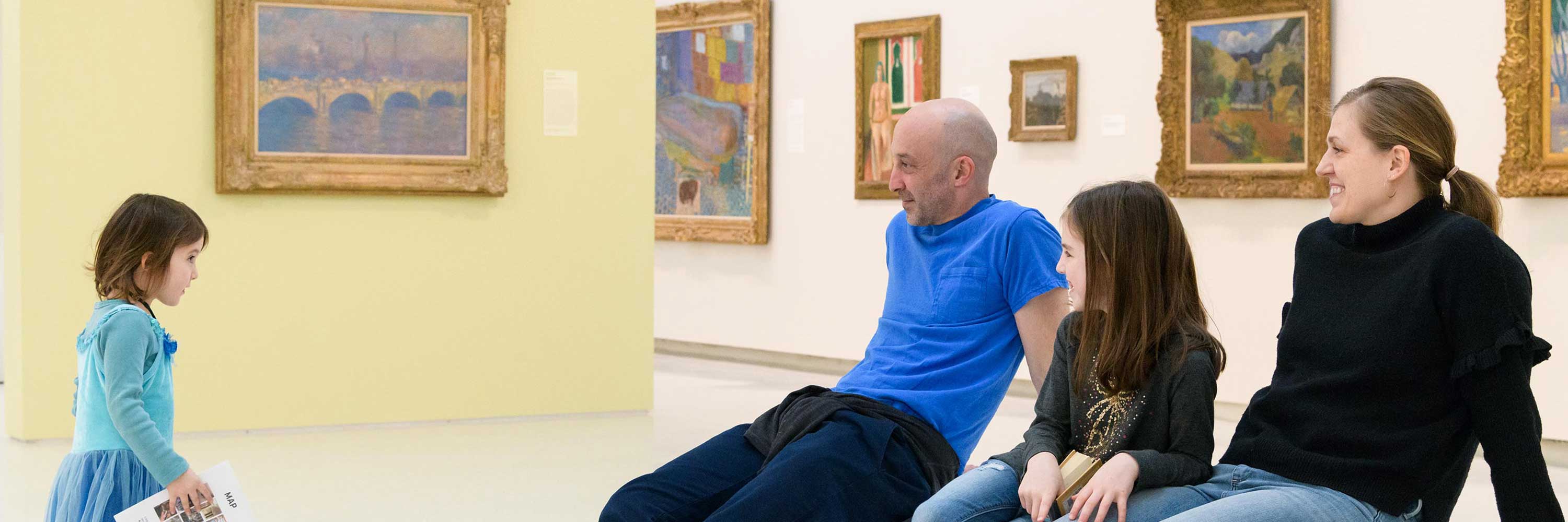 A family sits in the galleries, smiling at each other.