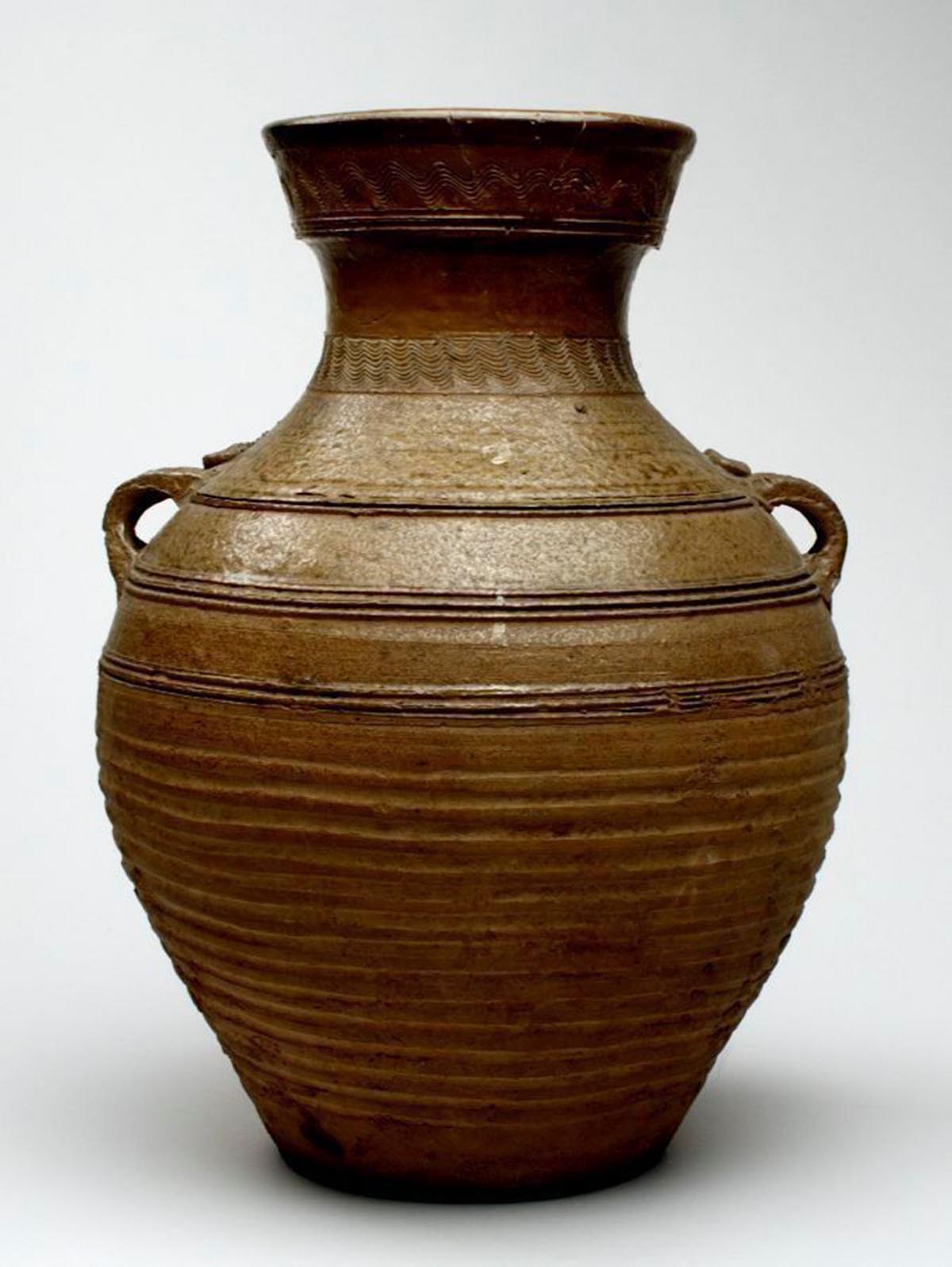 A earth-toned ceramic vase with small handles below the neck. 
