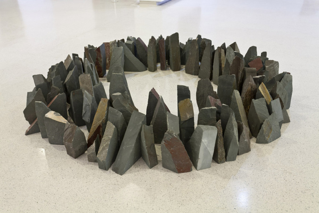 A grouping of sharp, dark stones form a ring in the middle of the museum floor.