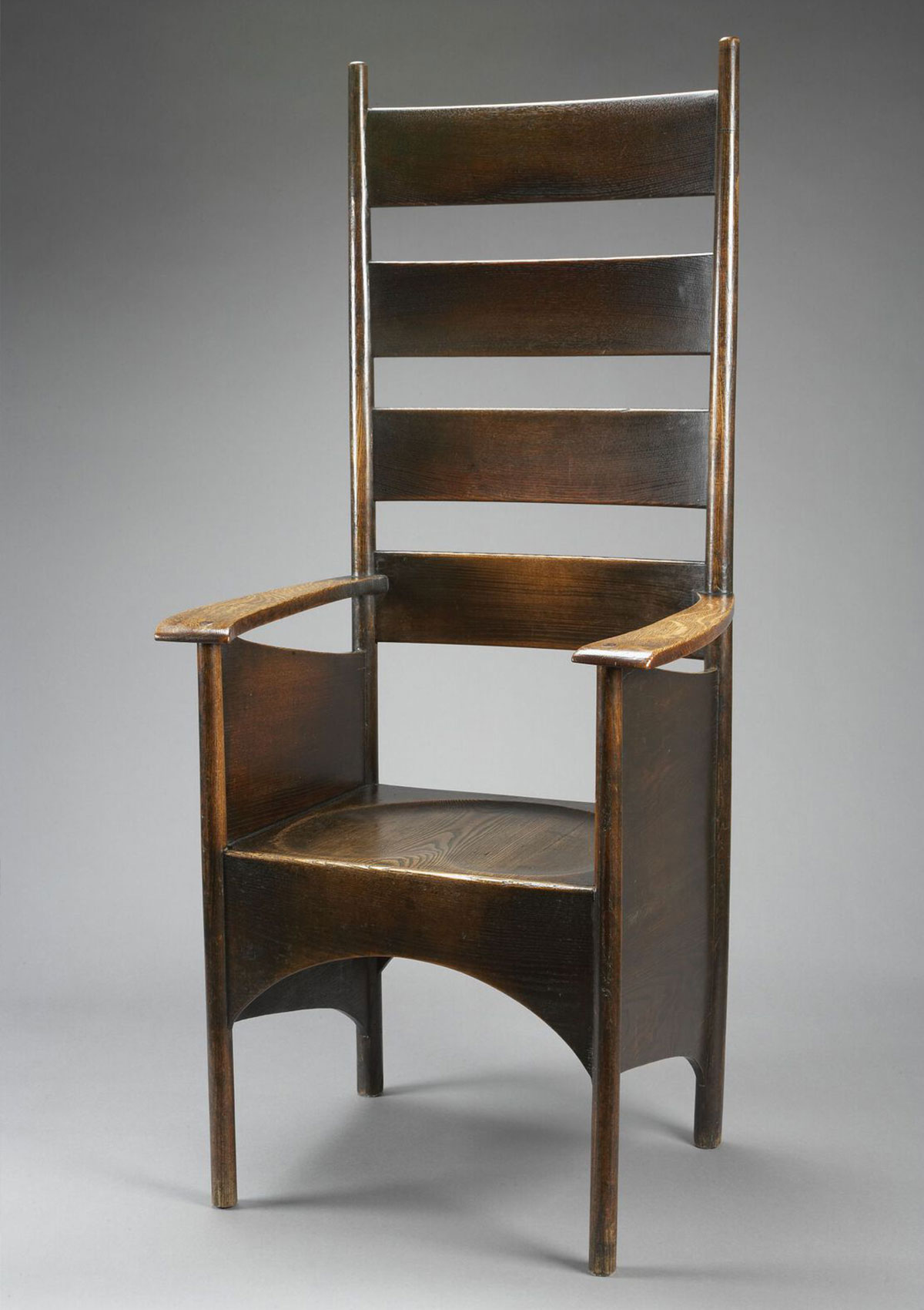 A tall, wooden chair with a high back comprised of four slats. Its narrow arms that connect to the seat with wide panels