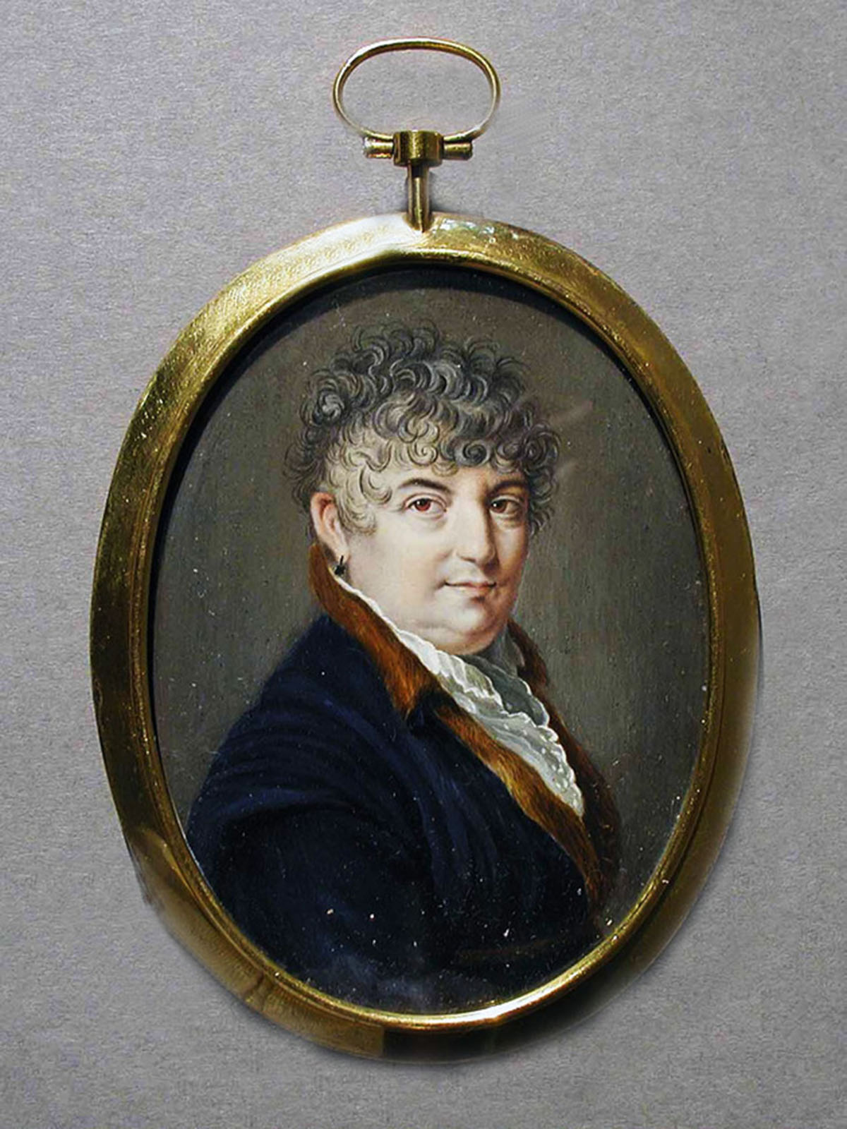A miniature watercolor portrait of a middle-aged woman is painted on an oval-shaped piece of ivory with a gold frame.