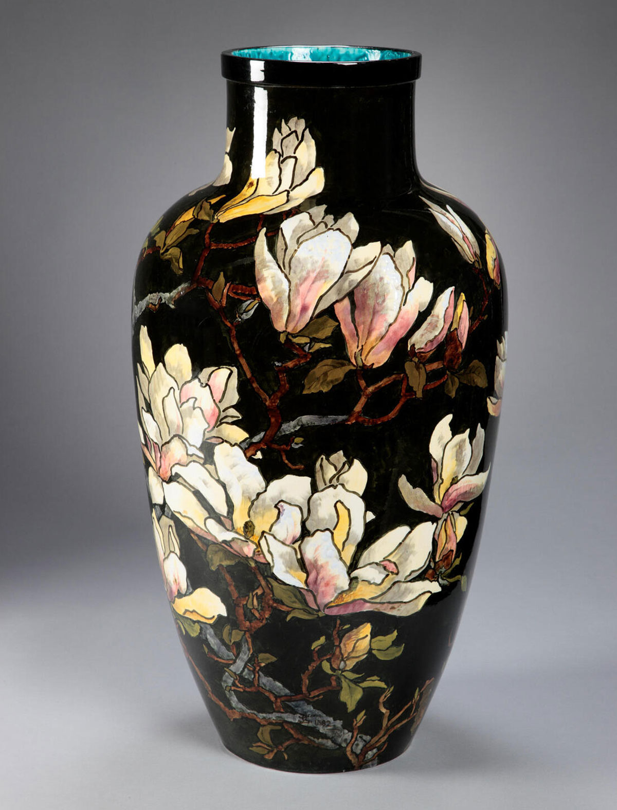 A tall ceramic vase with pale white and pink flowers painted onto a dark surface. The inner rim of the vase, barely visible at the top, is a bright turquoise