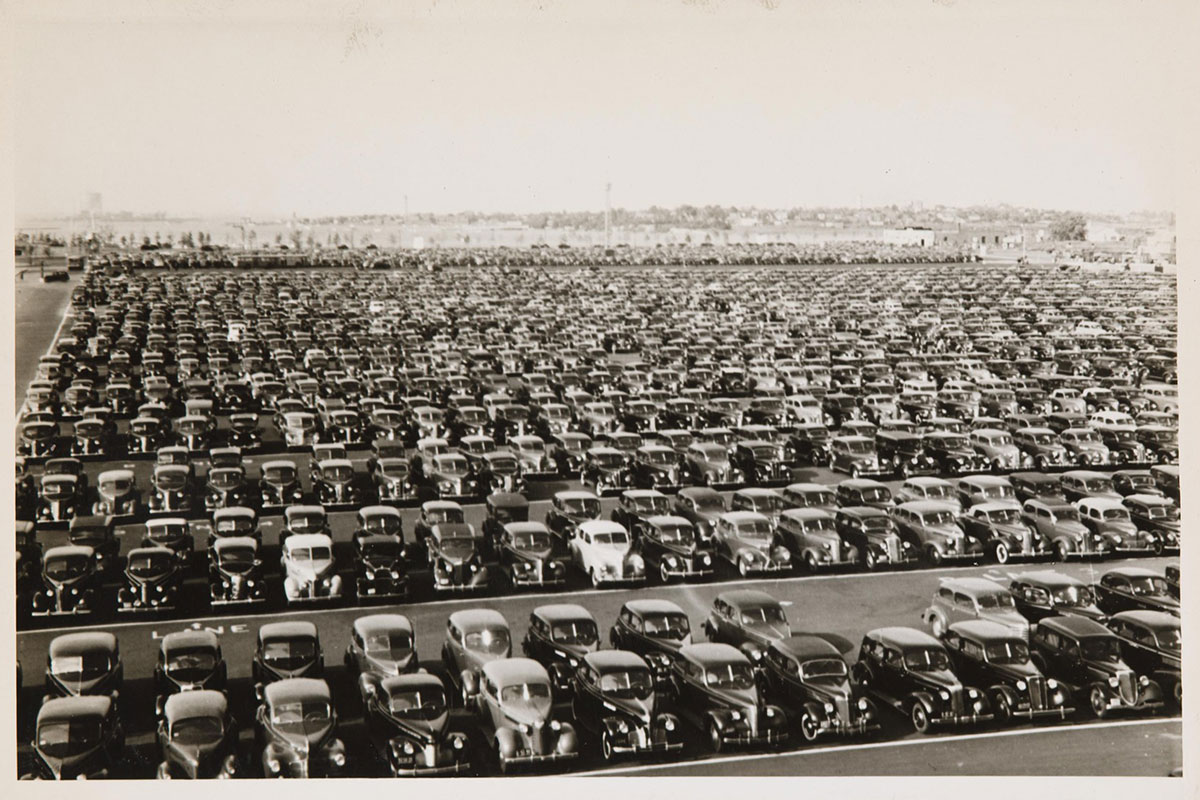 Hundreds of old-fashioned cars are lined up across a wide parking lot.