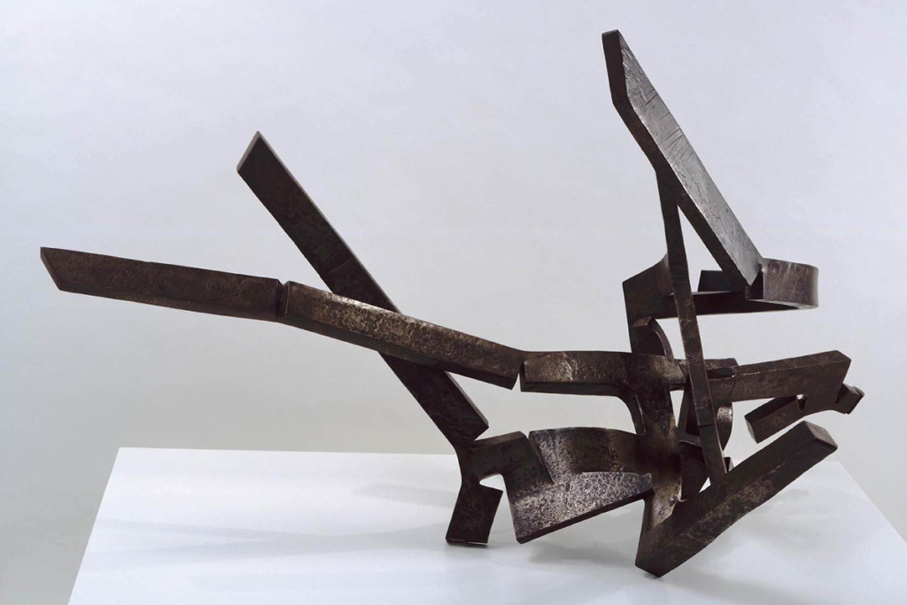 An abstract, textured, dark metal sculpture made of thin, angled arms