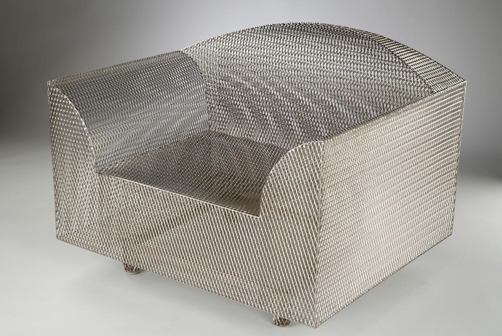 A wide armchair made of steel mesh
