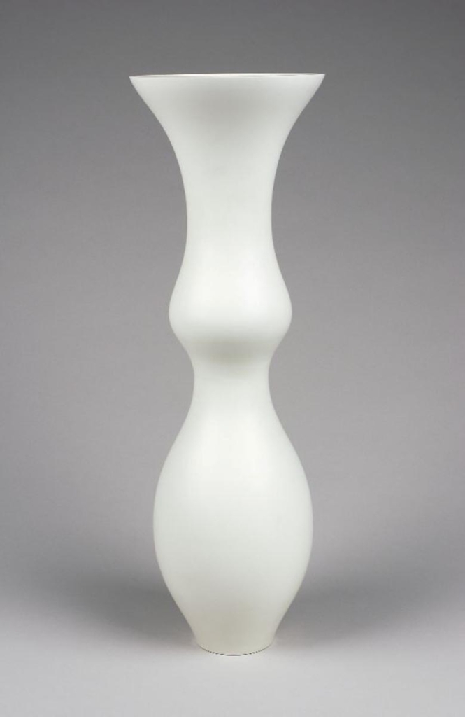 A tall, white vase stands against a white background