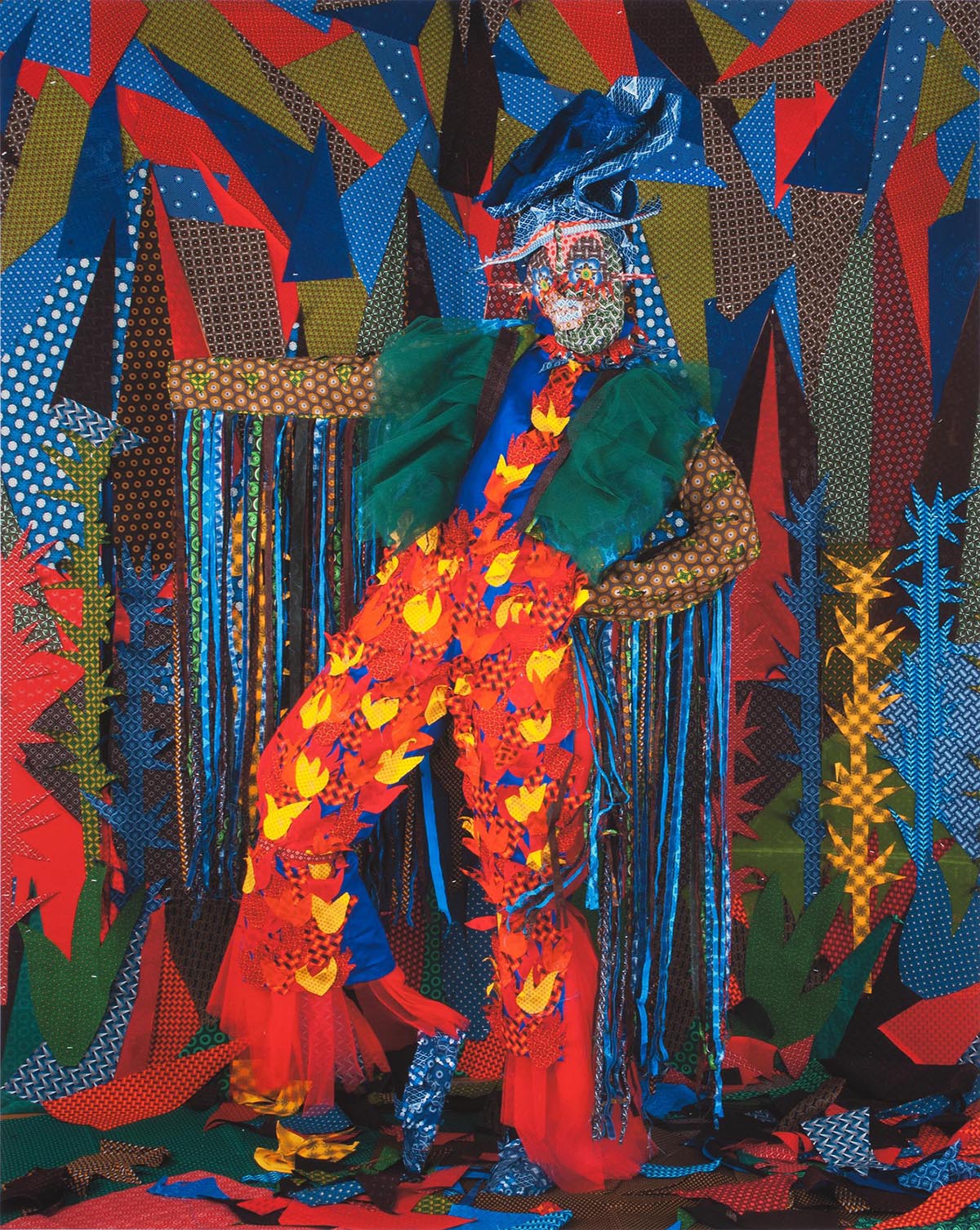  A person wearing a colorful mask and costume covering their whole body poses in front of a brightly patterned backdrop 