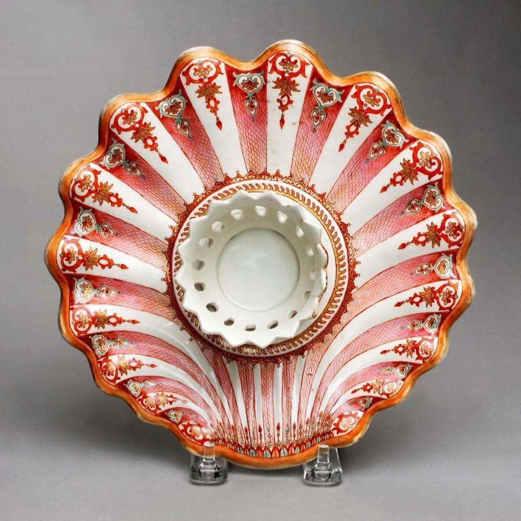 A small, ornately decorated plate shaped like a shell and a lotus with a raised ring in the center