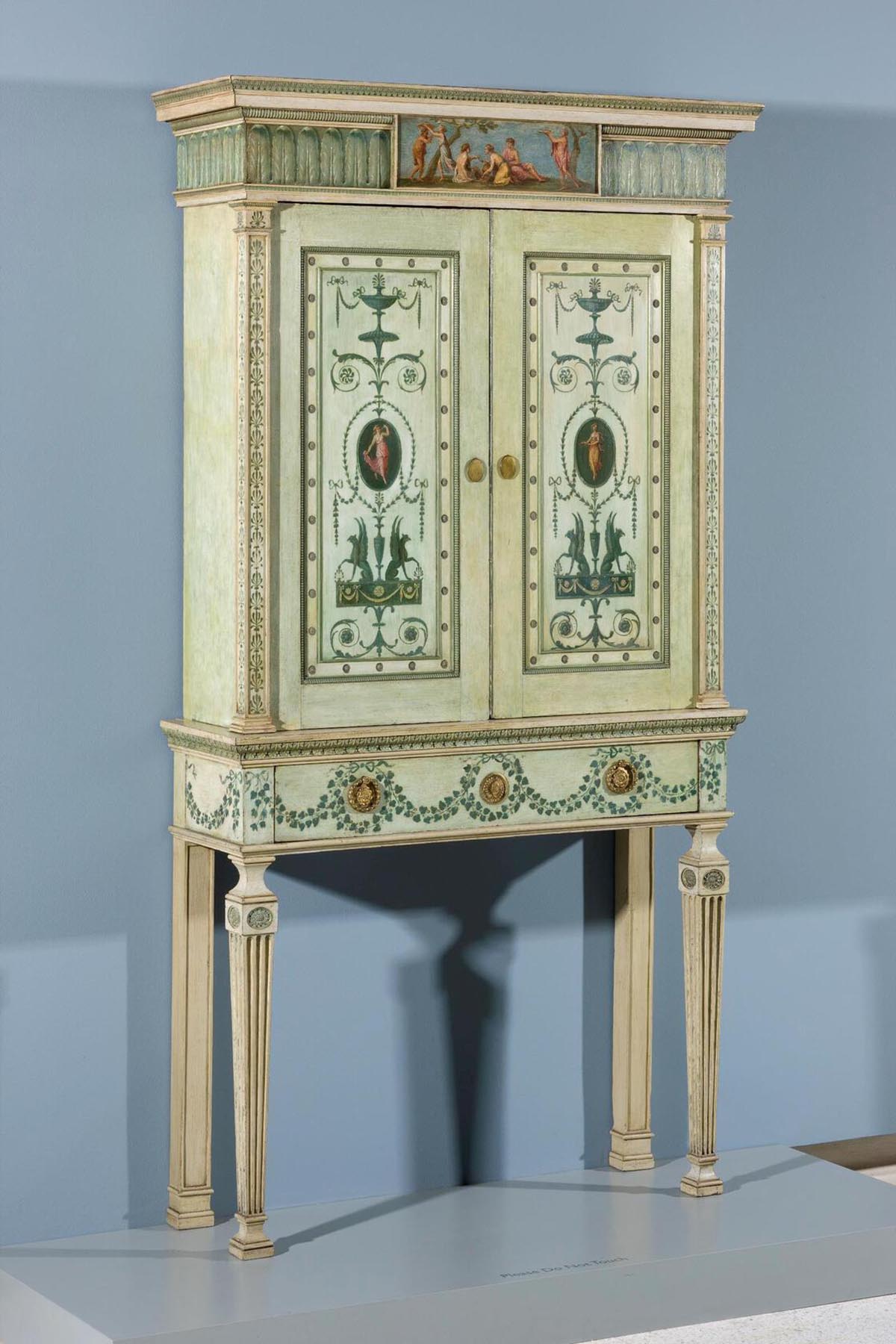 A wooden bookcase painted light green with additional decorations on the surface