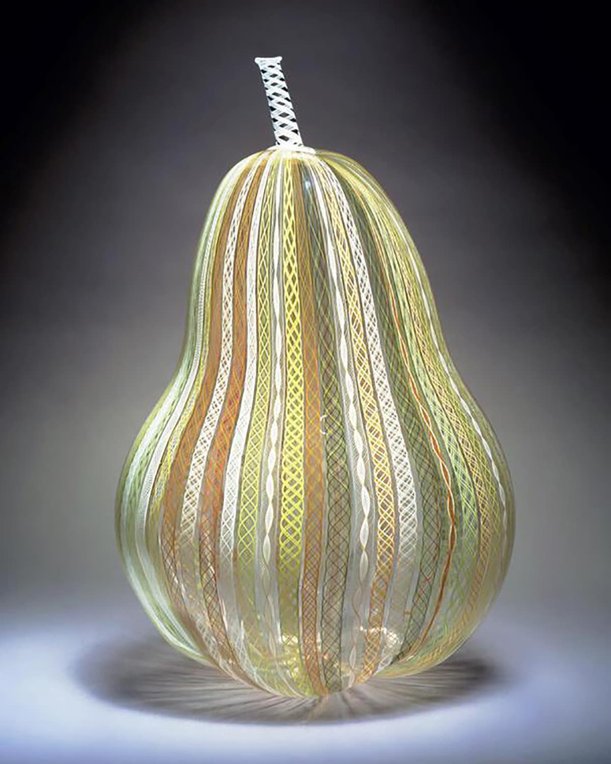 Studio image of a glass sculpture that is in the shape of a pear.