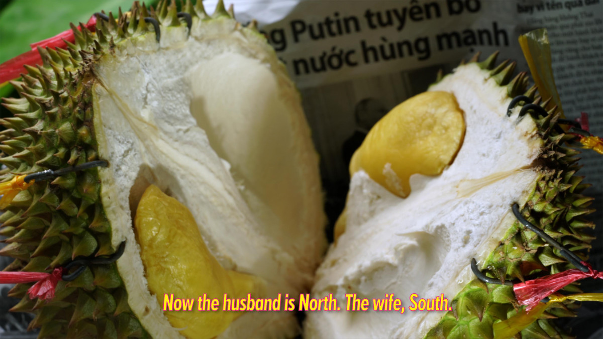 Video still with a detail of a Durian fruit split in half and caption "Now the husband is North. The wife, South."