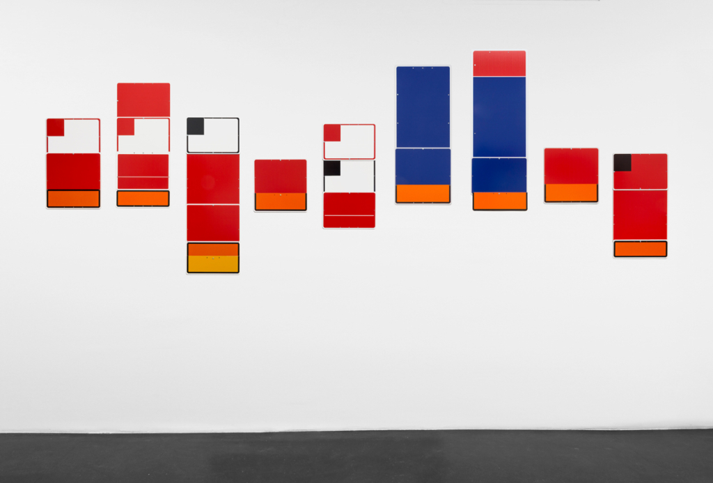 Rectangular paintings hung in a line. Each painting is comprised of smaller squares inside the rectangular canvas.
