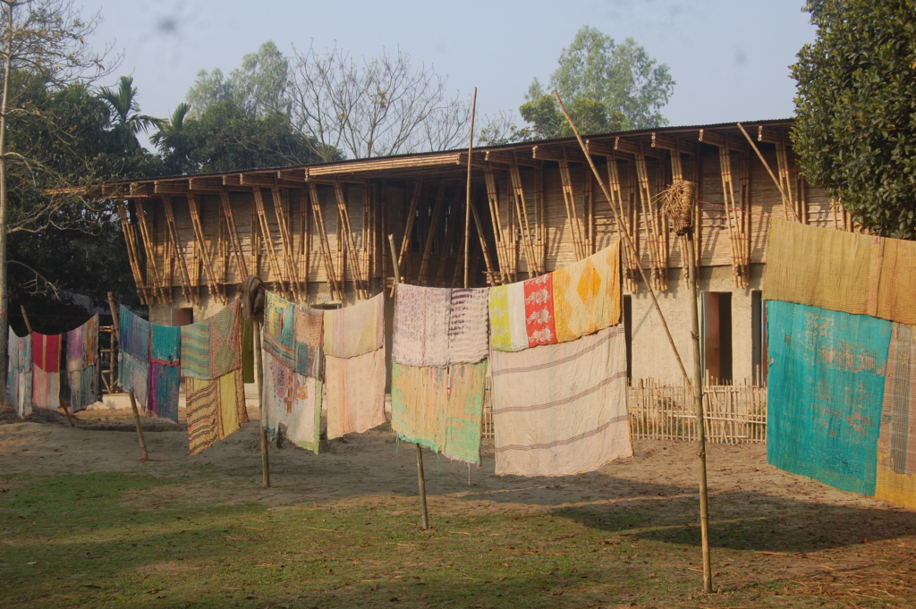 Photograph of striking textiles hanging in front of a building.
