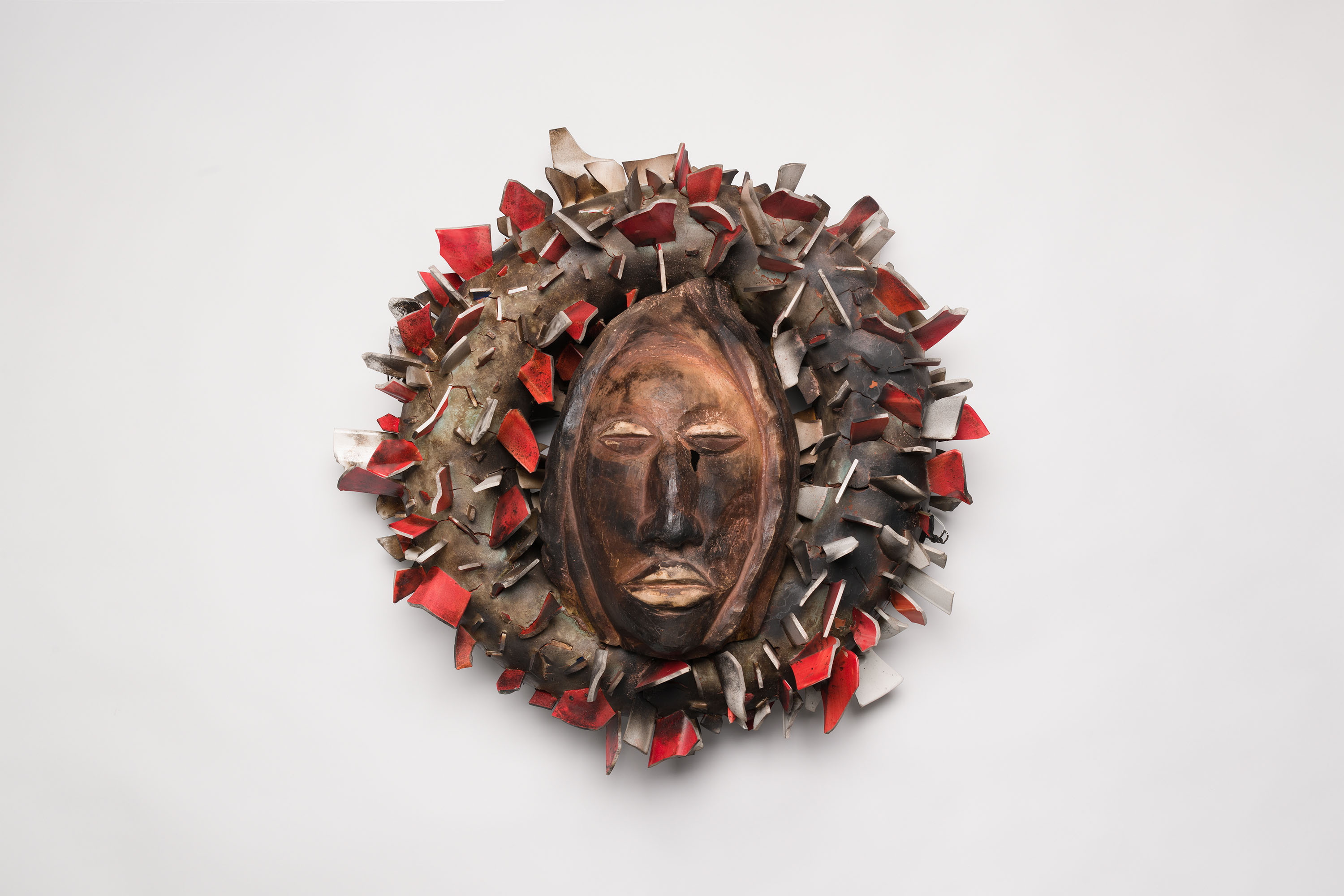 a ceramic artwork consisting of a wreath around a face