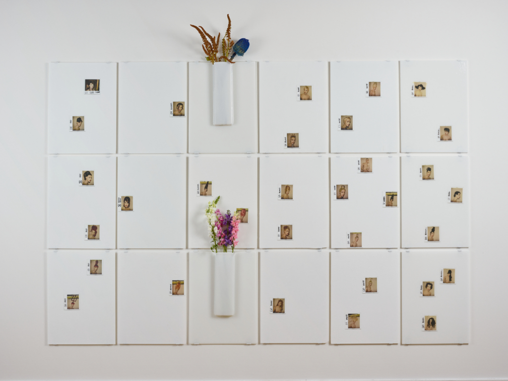 An art installation using white paper, dried flowers, and small images