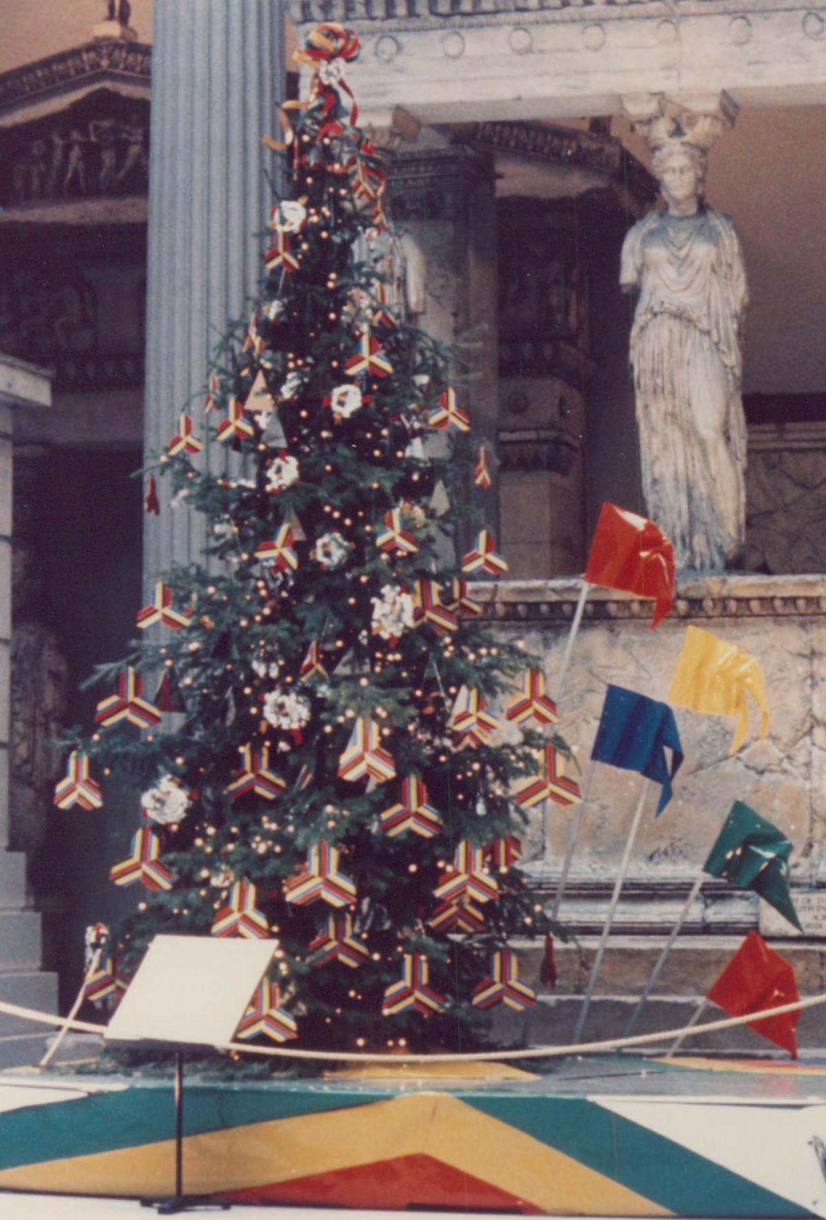 A colorful tree in front of a statue.