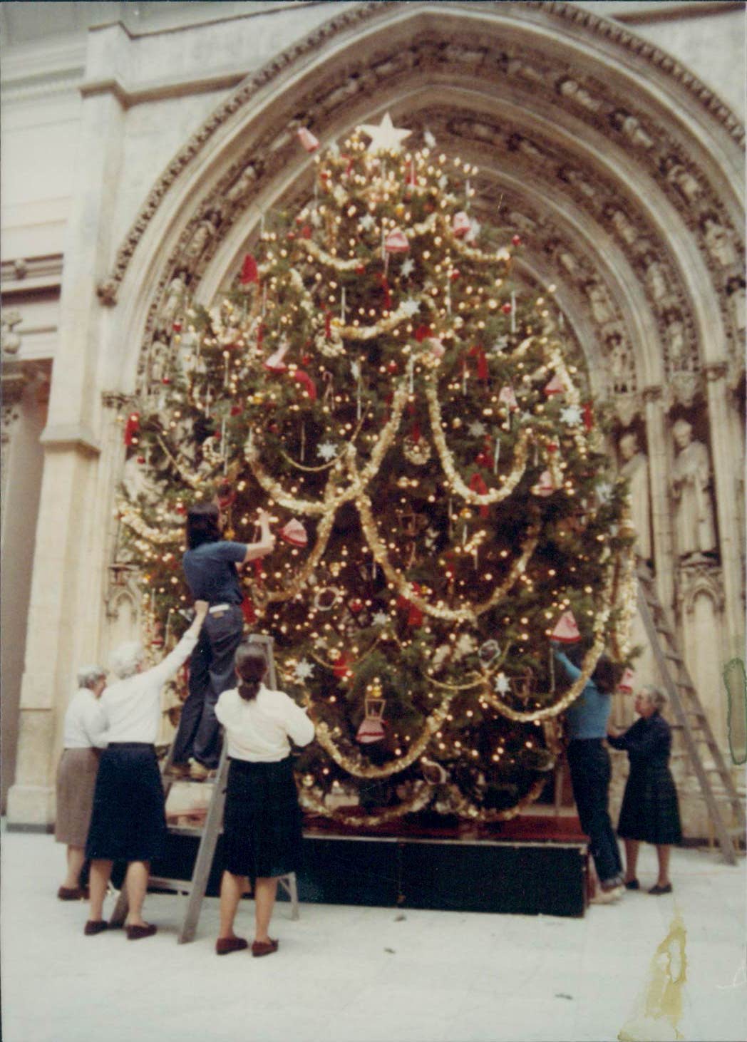A group of women decorate a tree.