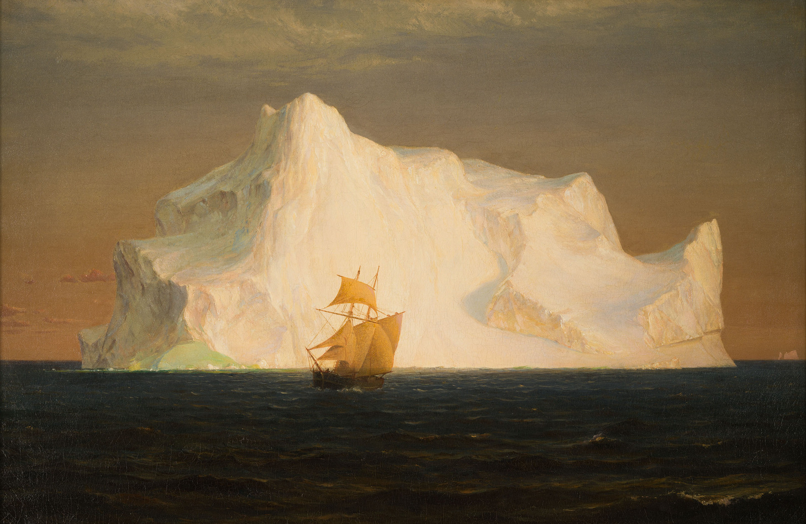 a boat sails in the shadow of a large Iceberg.