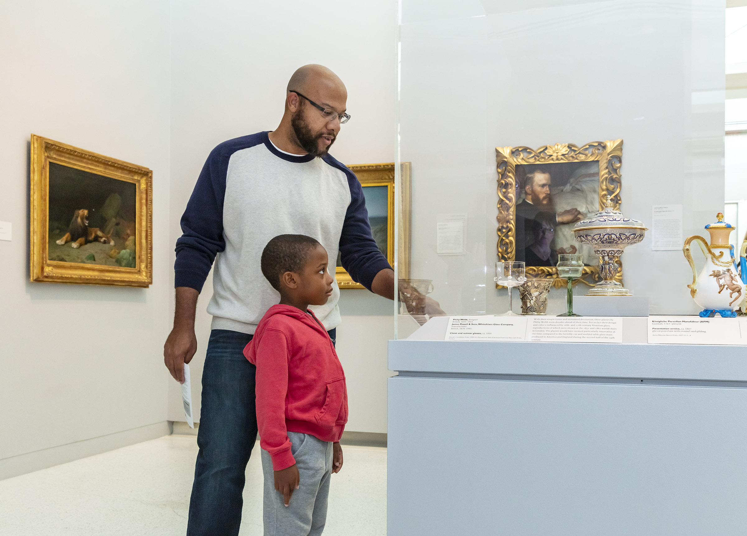 A father and son look art art objects behind glass