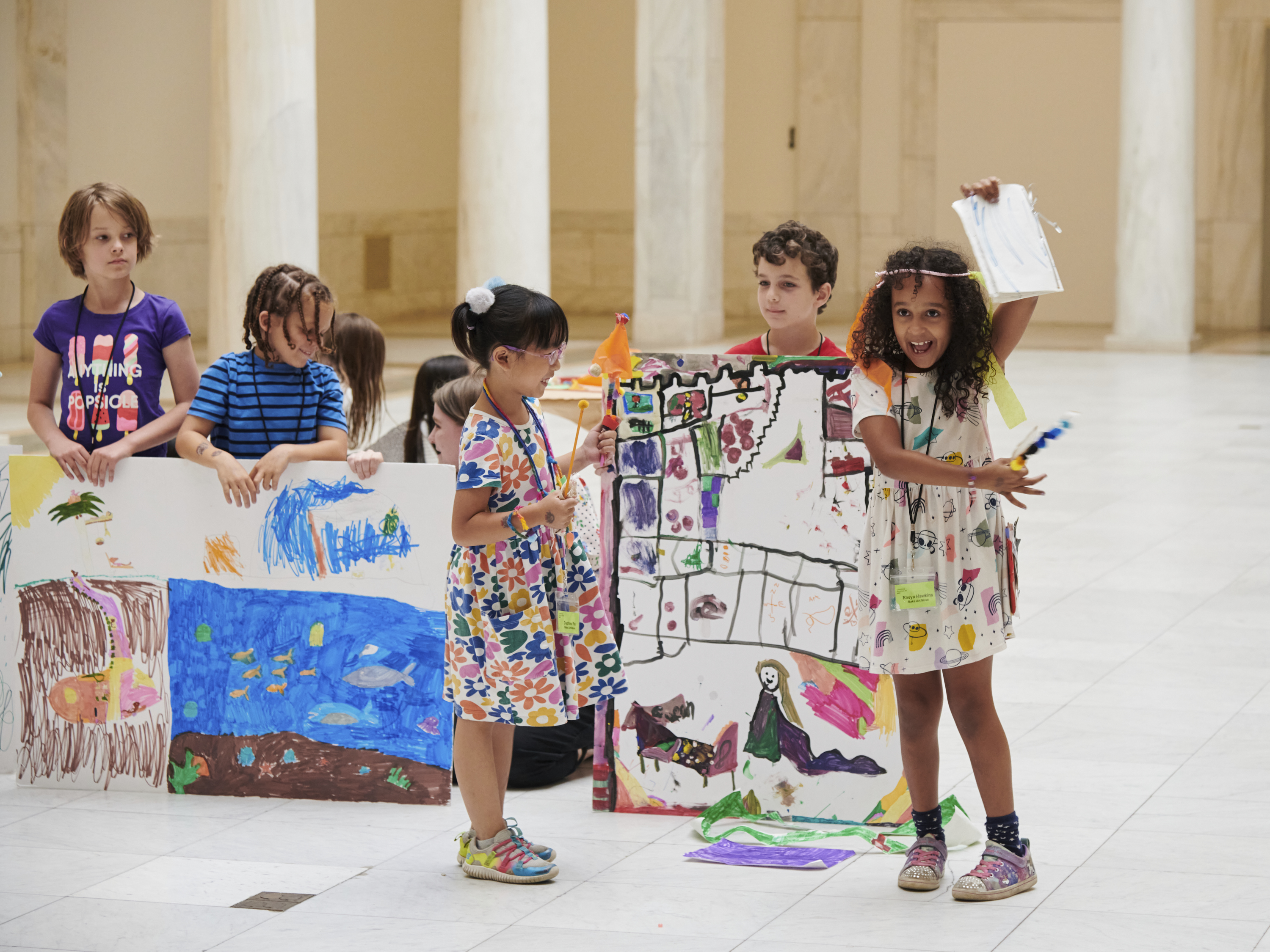 Kids hold up their art works