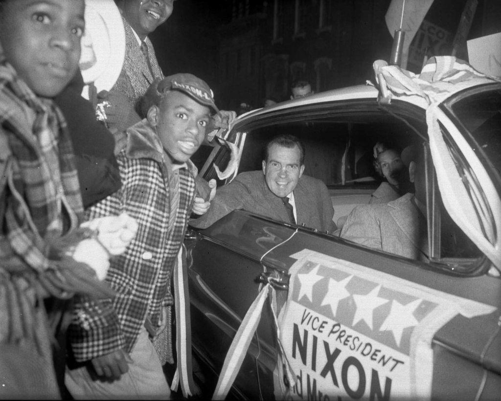 Vice President Richard Nixon and Pat Nixon greeting crowd from car, including Harold Irwin