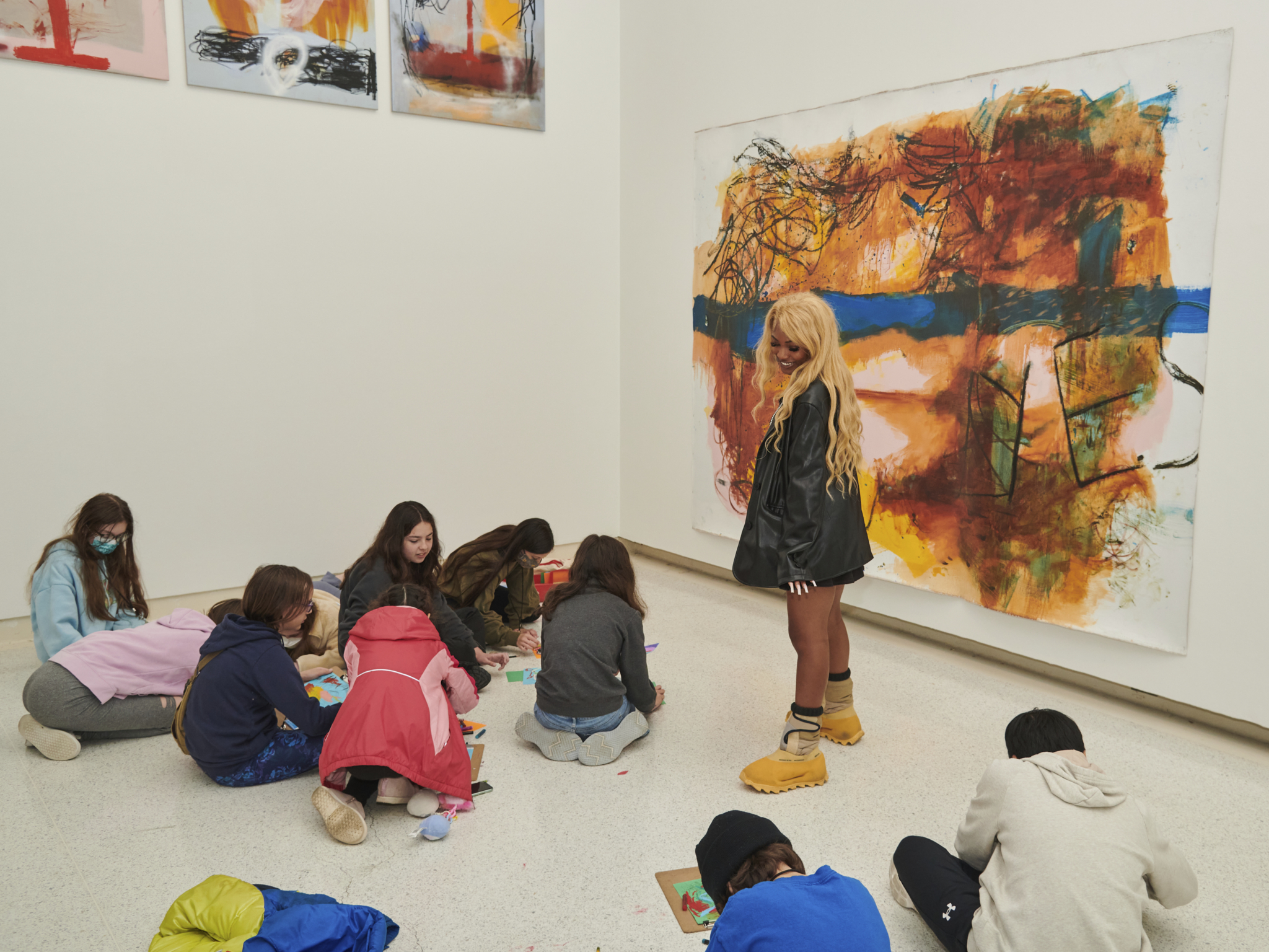 Students and a teacher drawing in front of a work of art.