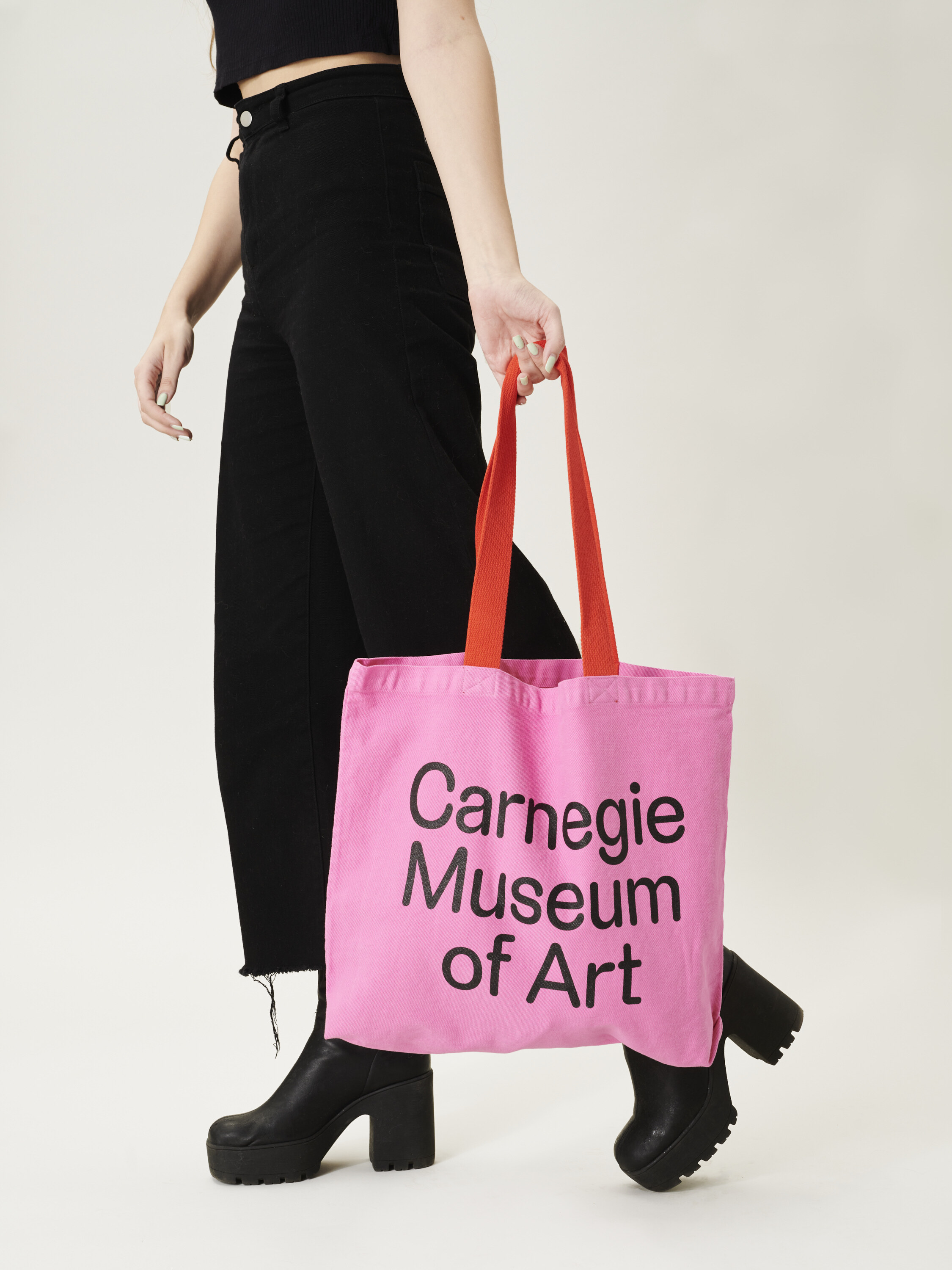 person holding the new Carnegie museum of art tote bag featuring the carnegie soft font