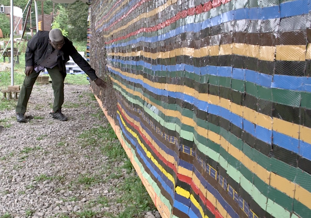 A man puts his hand on an art mural made of different tape tiles