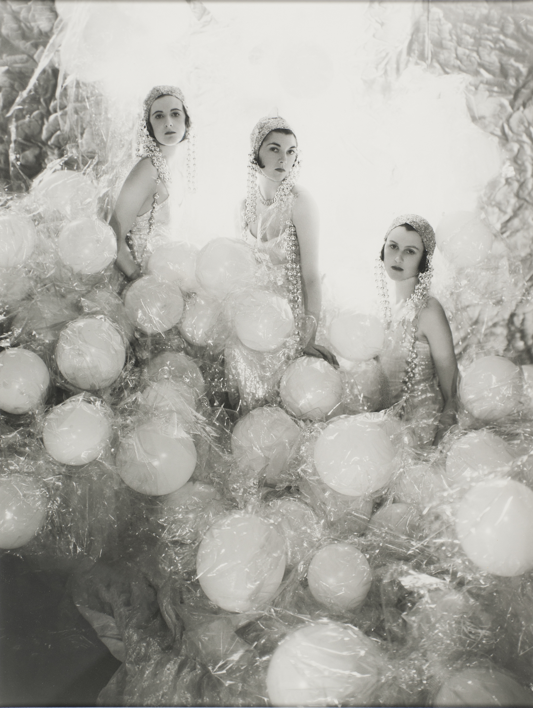 A black and white photo of three women dressed in large gowns made of balloons