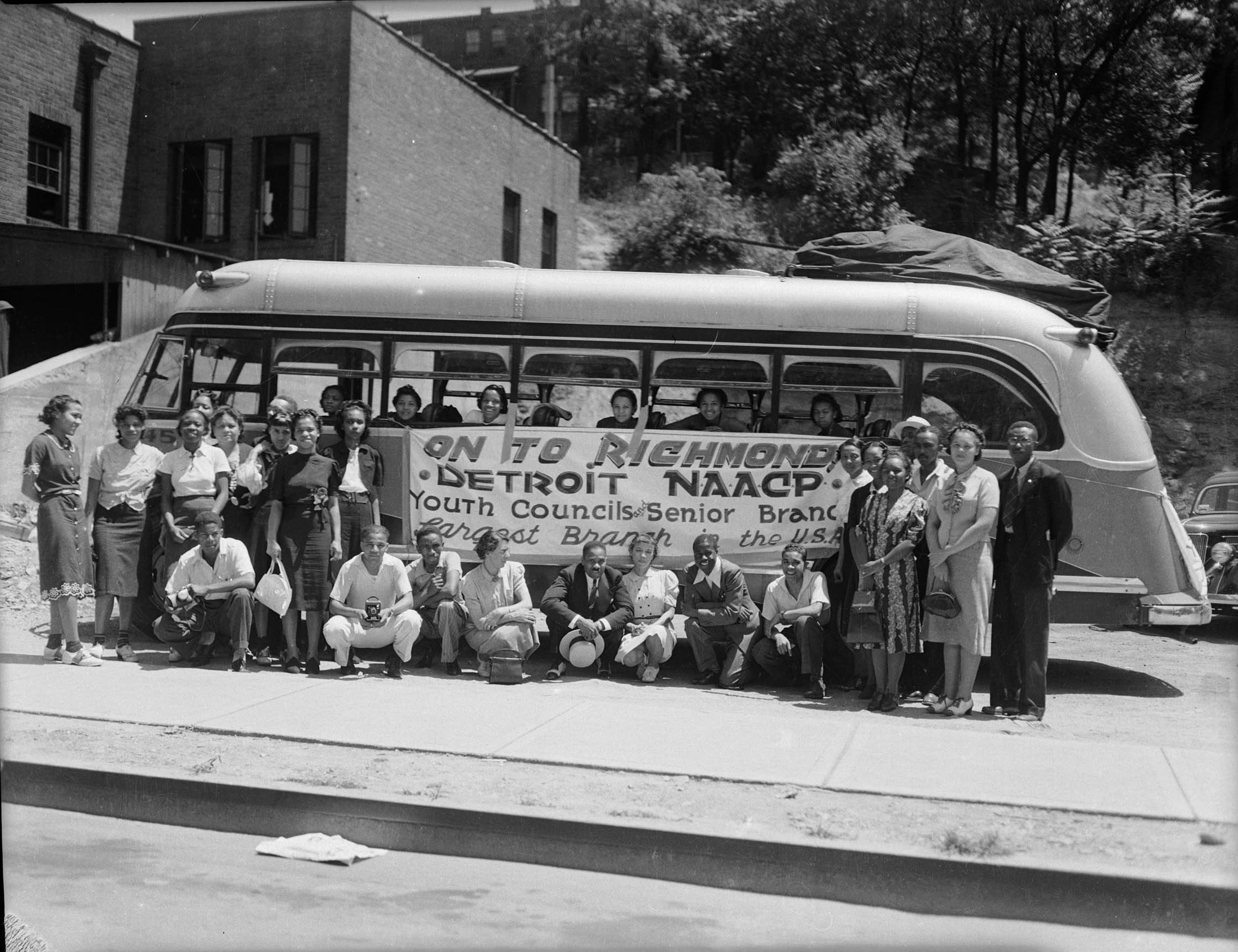 Charles "Teenie" Harris Exhibition Image depicting Men and women gathered in and around bus with banner reading On To Richmond, Detroit NAACP, Youth Councils and Senior Branch, Largest Branch in the USA
